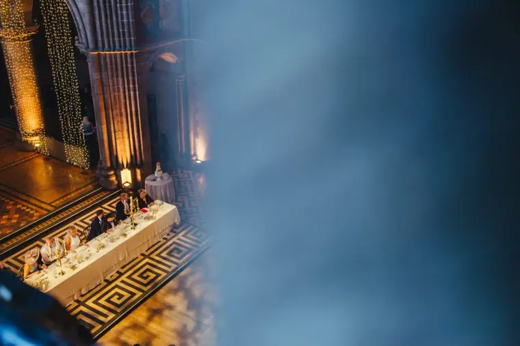 Top table seen from the gallery, framed by blurred blue stonework