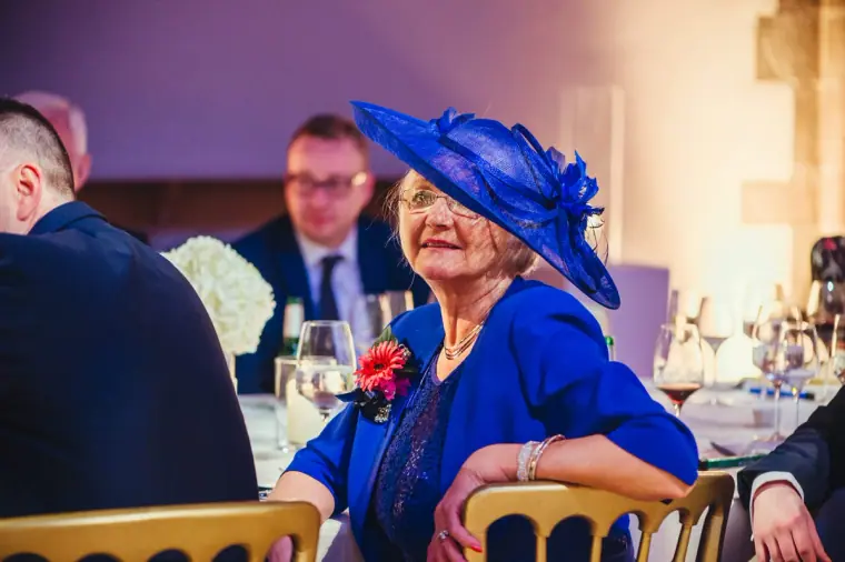 Guest in a royal blue hat smiling during the speeches