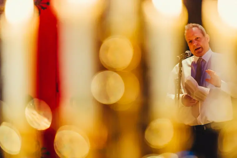 Guest delivering a speech seen through blurred candles