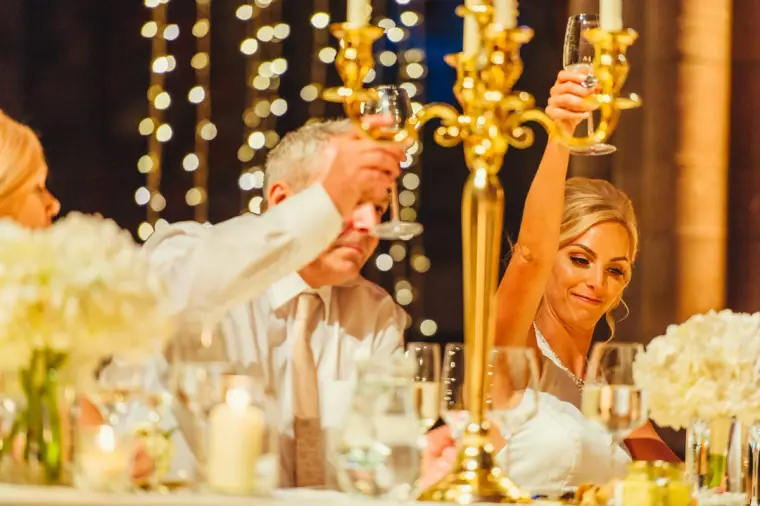 Guests raising a toast beside a gold candelabra at the top table