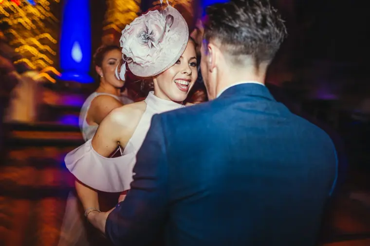Guest in a pink fascinator dancing with a man in a navy suit