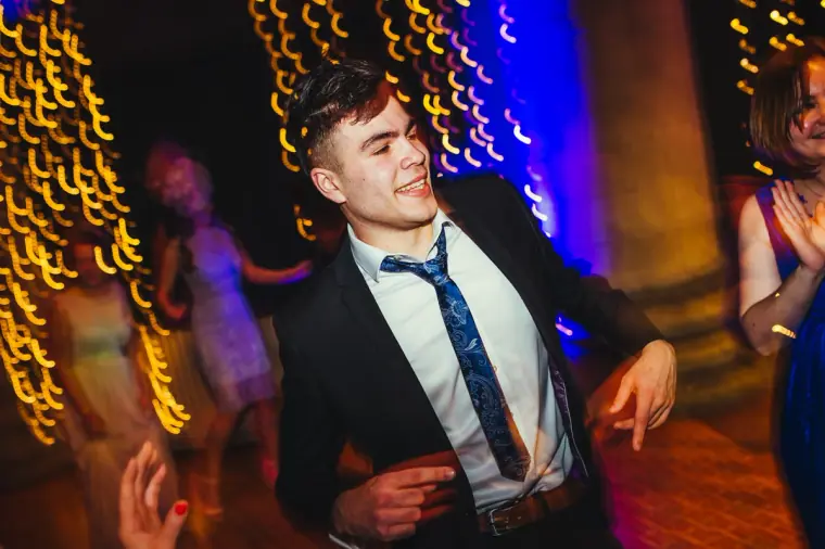 Guest in a navy suit dancing amid streaks of gold light
