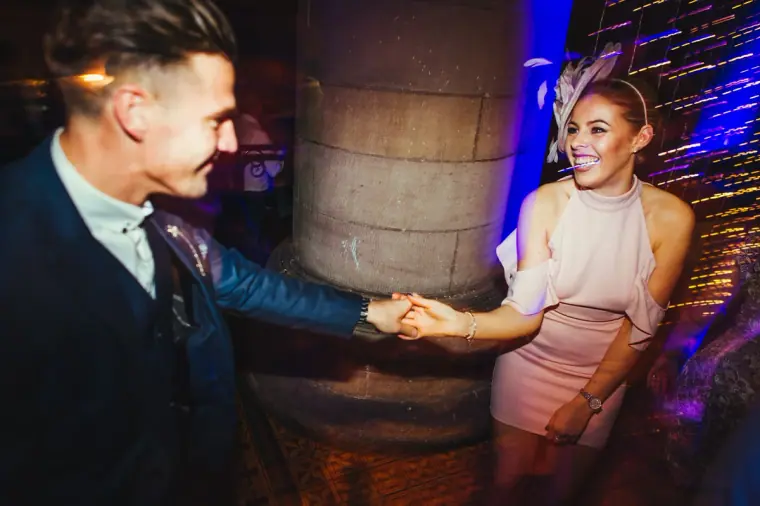 Man and woman holding hands mid-dance beside a pillar