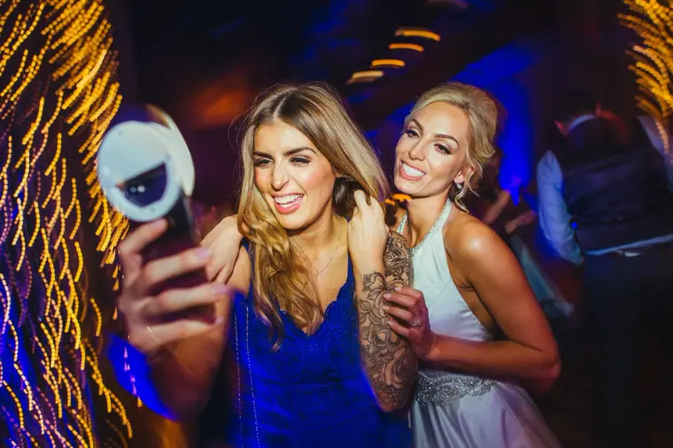 Bride and a friend taking a selfie with a ring light on the dance floor
