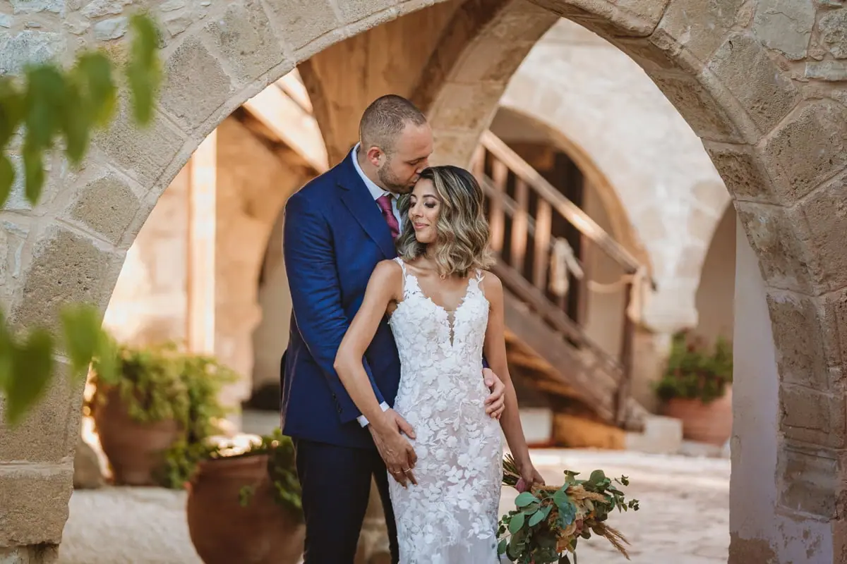 Emily and Chris embracing beneath a stone archway at Minthis, Paphos