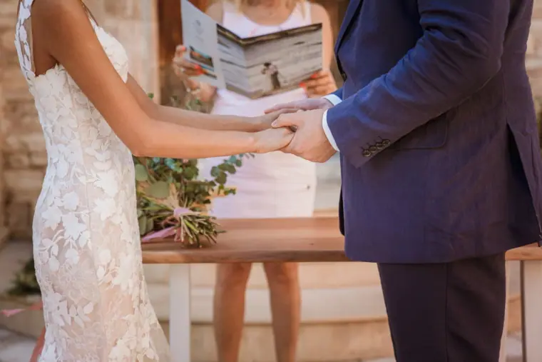 Bride and groom holding hands during the ceremony as the celebrant reads