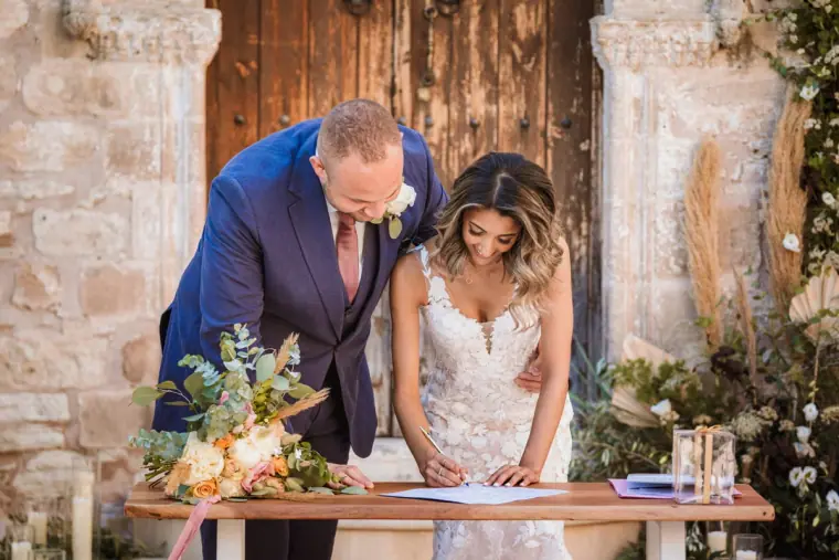 Bride and groom signing the register at a flower-decked table