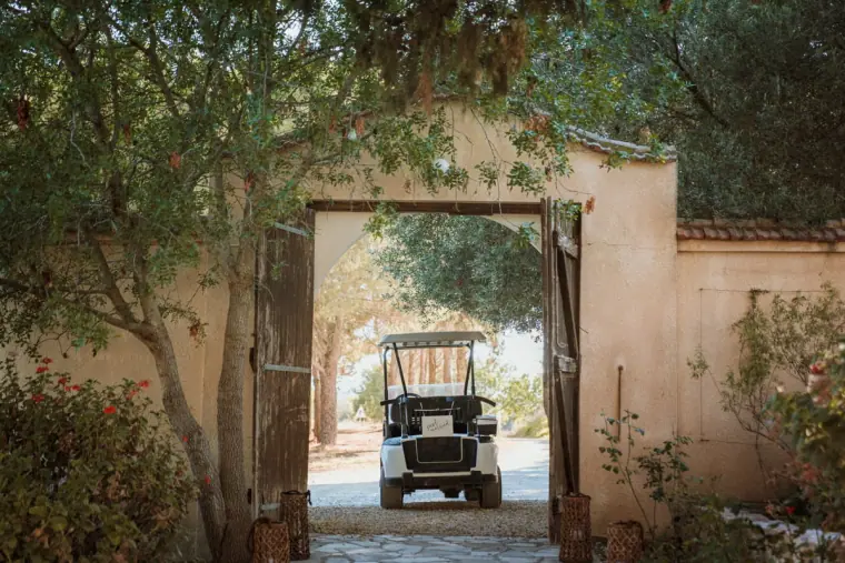 Open gateway in a sunlit wall revealing a golf buggy waiting outside
