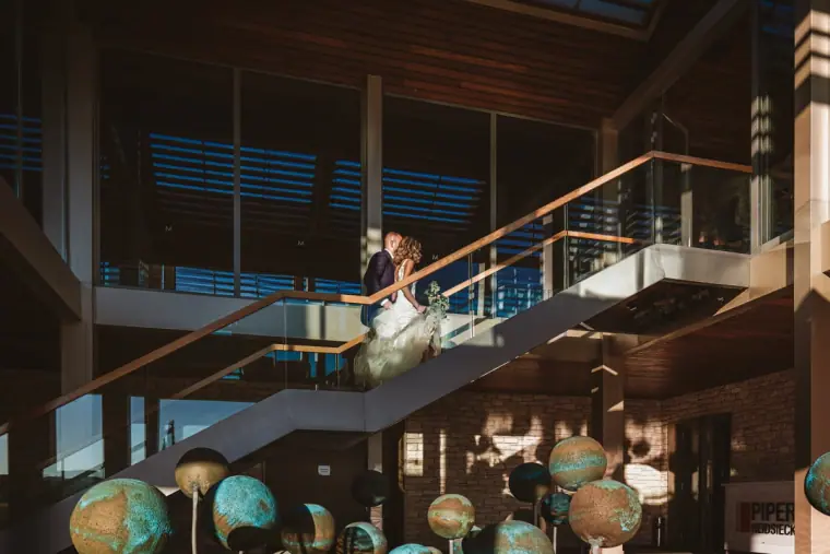 Bride on the glass staircase of a modern clubhouse with a display of globes