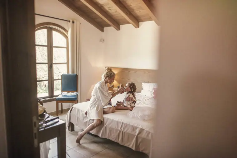Bride and a young girl sitting together on a bed in a beamed room