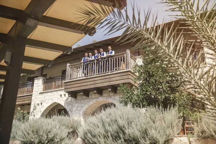 Groomsmen on a wooden balcony above lavender and palm trees at Ayii Anargyri