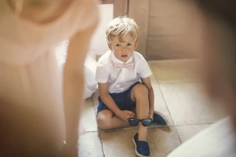 Page boy sitting on the floor pulling on his shoes