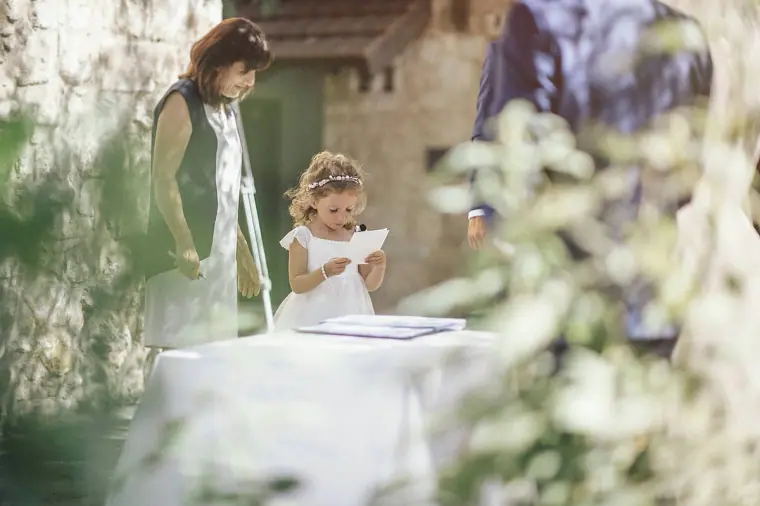 Flower girl reading at the ceremony table beside the officiant