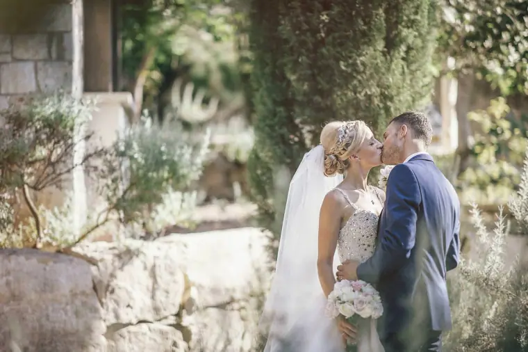 Emmee and Danny kissing in a garden beside stone steps