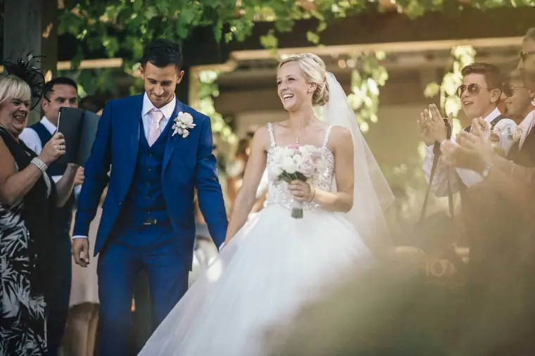 Emmee and Danny laughing as guests cheer them out of the venue