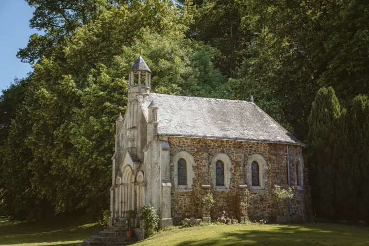Small stone Gothic chapel among tall trees in the château grounds