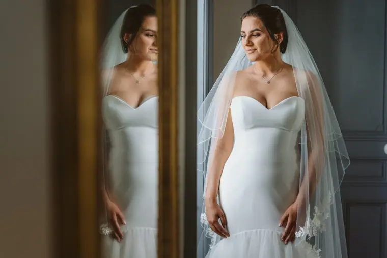 Lauren in a strapless gown and veil reflected in a tall mirror at Château de la Basmaignée
