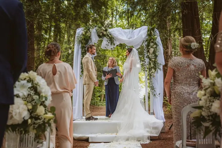 Lauren and Josh at the draped floral arch during their woodland ceremony