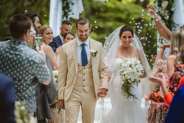 Lauren and Josh walking back up the aisle through falling confetti in the forest