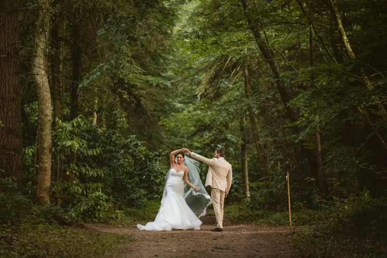 Lauren twirling her veil beside Josh on a forest path