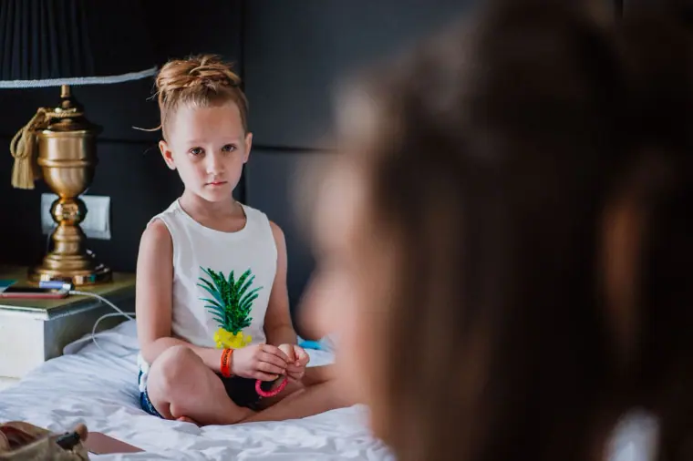 Young pageboy sitting cross-legged on the hotel bed during getting ready
