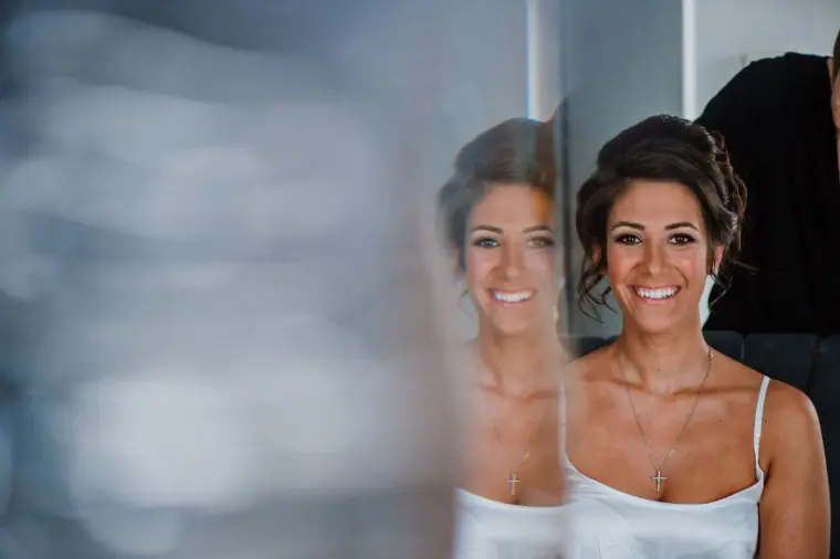 Louise smiling at her reflection in a mirror while getting ready