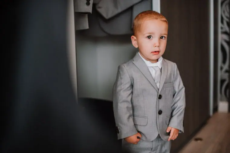 Young pageboy in a grey suit standing in a doorway
