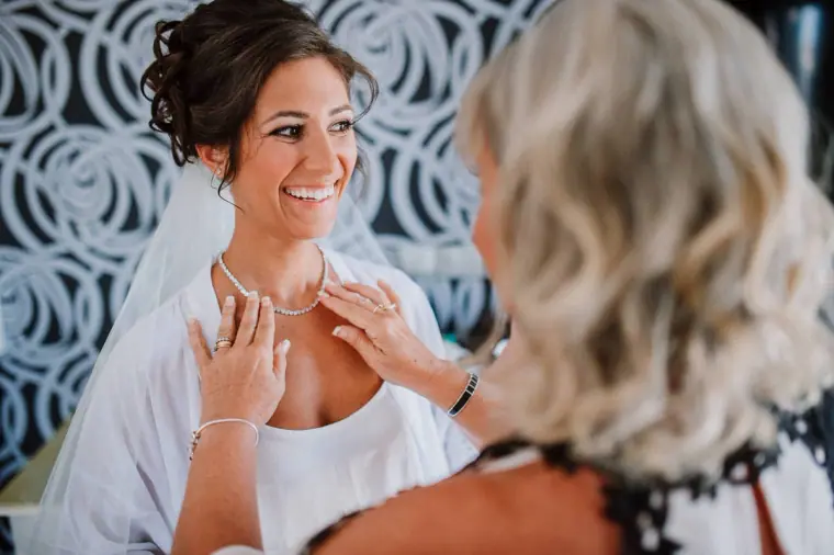 Louise smiling as a woman fastens her necklace