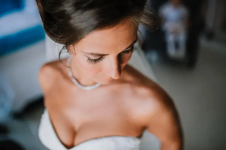 Louise looking down in her strapless gown and pendant necklace
