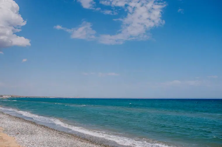 Turquoise sea and shingle beach under a blue sky at Galu Seaside