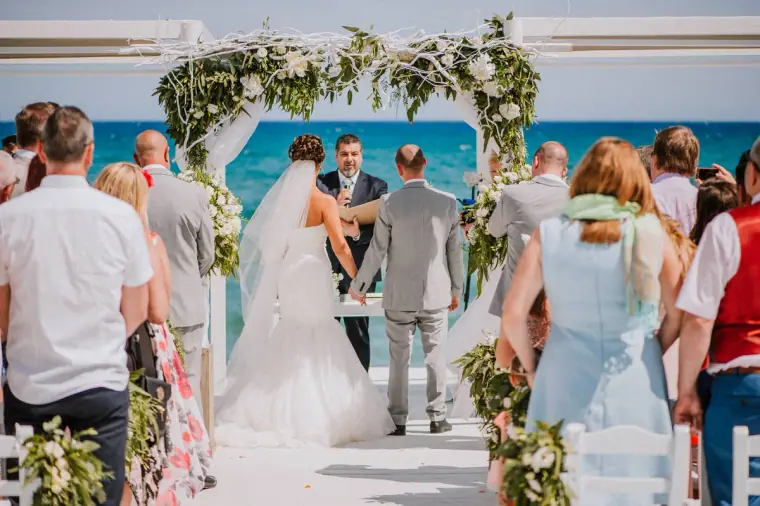 Louise and Mike at the floral arch before the sea during the ceremony