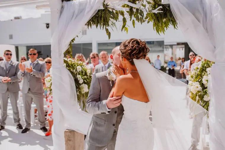 Louise and Mike embracing under the arch as guests look on