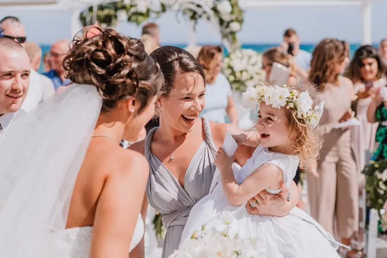 Louise laughing with a bridesmaid holding a flower girl in a floral crown