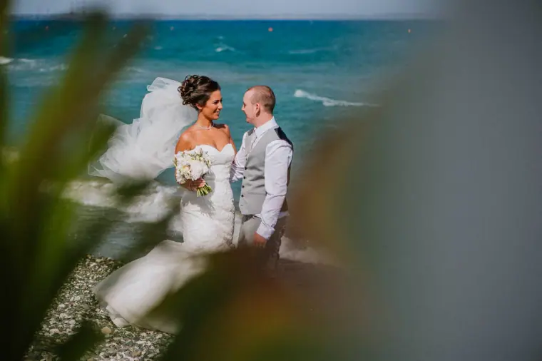 Louise and Mike by the sea, glimpsed through blurred leaves in the foreground