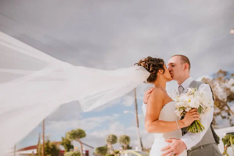 Louise and Mike kissing as her long veil flies in the wind