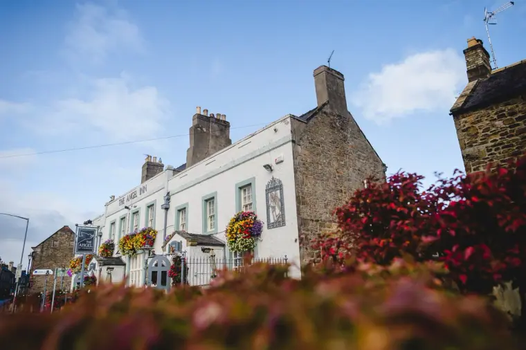 The Angel of Corbridge inn and neighbouring stone buildings behind red flowers