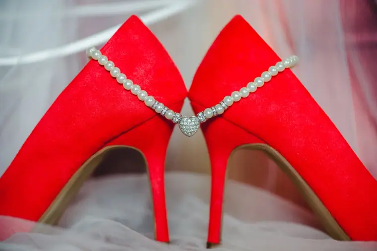 Red suede bridal heels joined by a diamanté shoe chain