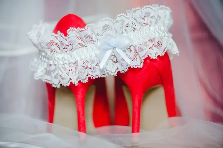 Lace garter resting on top of red bridal heels