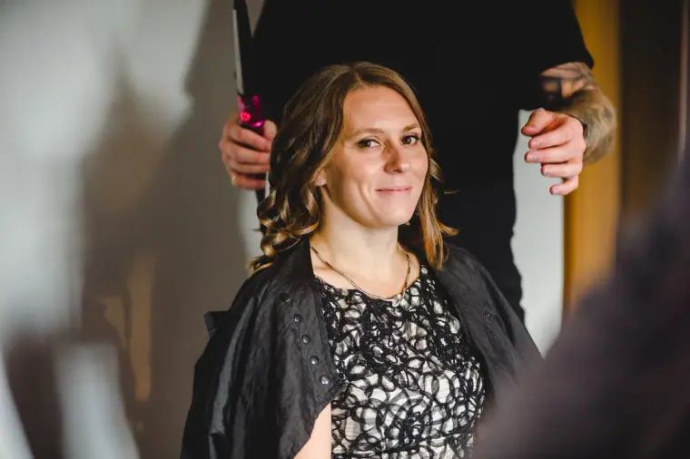 Woman in a black lace dress smiling during the bridal preparations