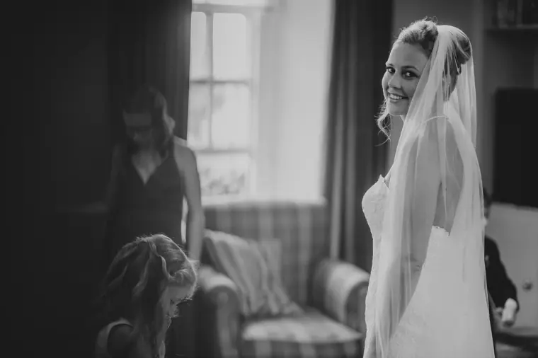 Black-and-white photo of the bride glancing back over her shoulder in her veil