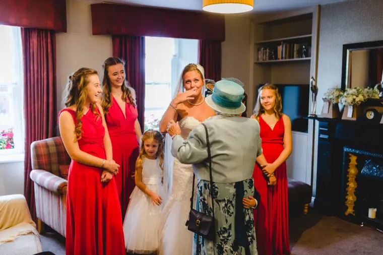 Bridesmaids in red dresses watching as the bride is greeted in the lounge