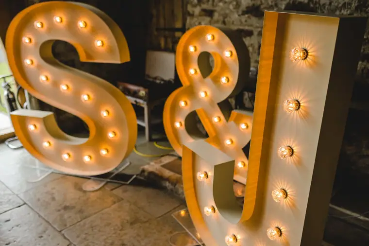 Giant light-up S&J marquee letters on the flagstone floor at Healey Barn