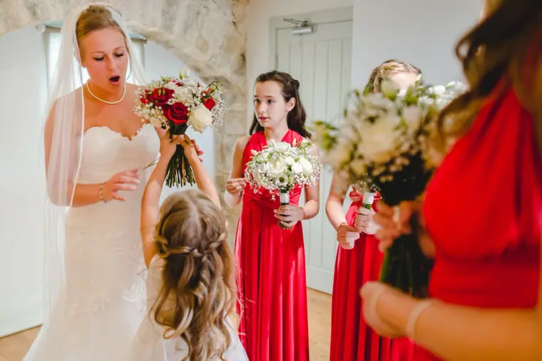 Bride greeting bridesmaids in red dresses and a young bridesmaid before the ceremony