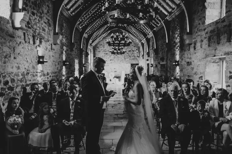 Black-and-white photo of the ceremony in the vaulted stone barn