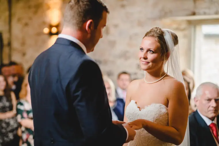 Bride smiling at the groom as they exchange rings