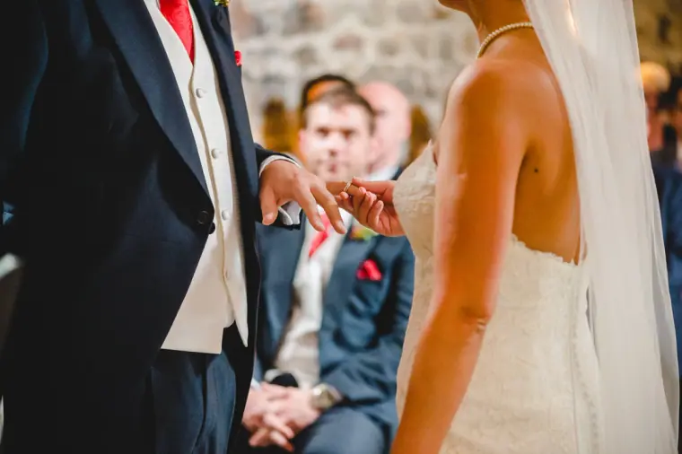 Close-up of the groom sliding the ring onto the bride's finger