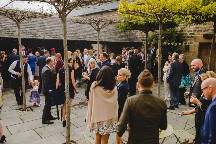 Guests mingling in the stone courtyard at Healey Barn