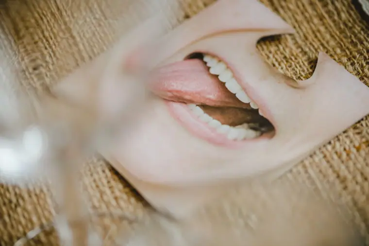 Cardboard smiling-mouth photo prop lying on a hessian table runner