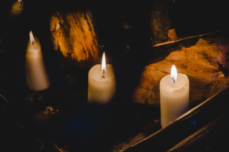 Pillar candles glowing in a dark stone alcove