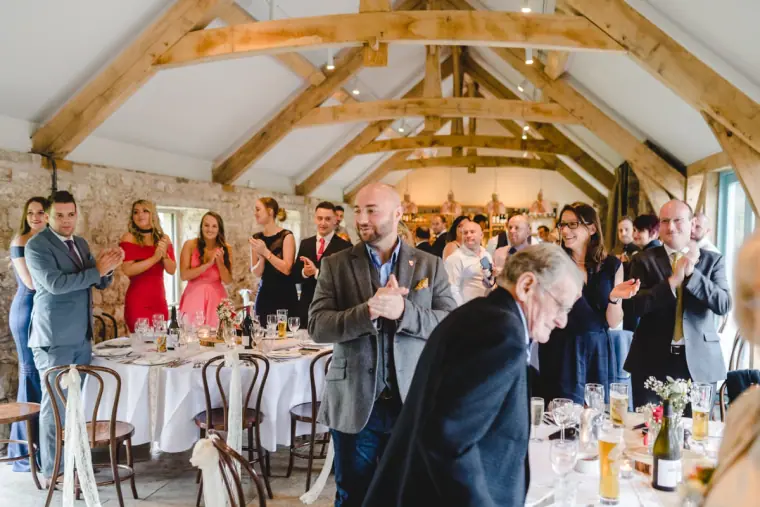 Guests standing and applauding as the couple enter the reception room